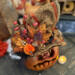 A close up of Wallace's hat. Its orange and brown brocade with a black sash. An arrangement of berries and pumpkins sit on the brim.